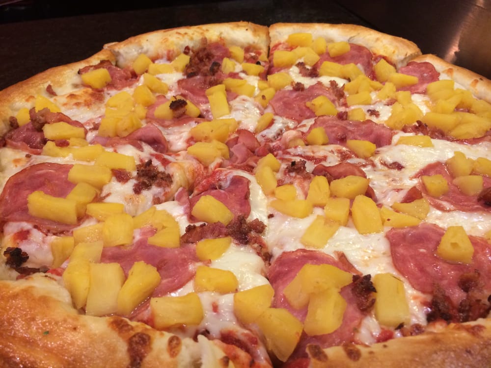 An image of pineapple pizza with ham and crumbled bacon as toppings.