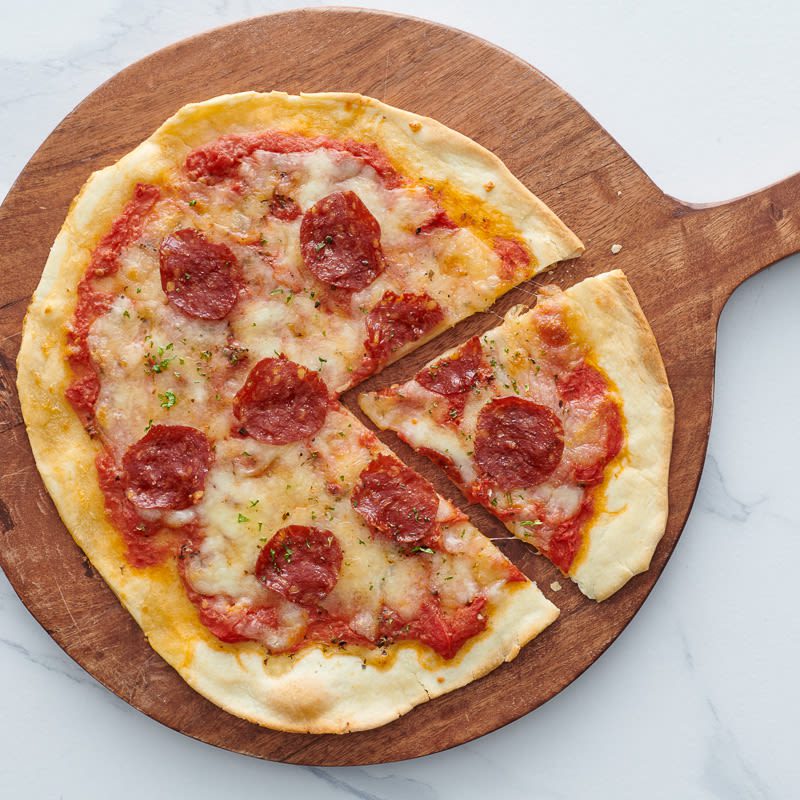 Image of a sliced turkey pepperoni pizza on a wooden tray
