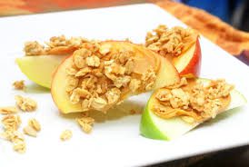 Top 10 Snacks Under 10 mins - Image of moon shaped apple slices coated with almond butter and granola served in a plate.